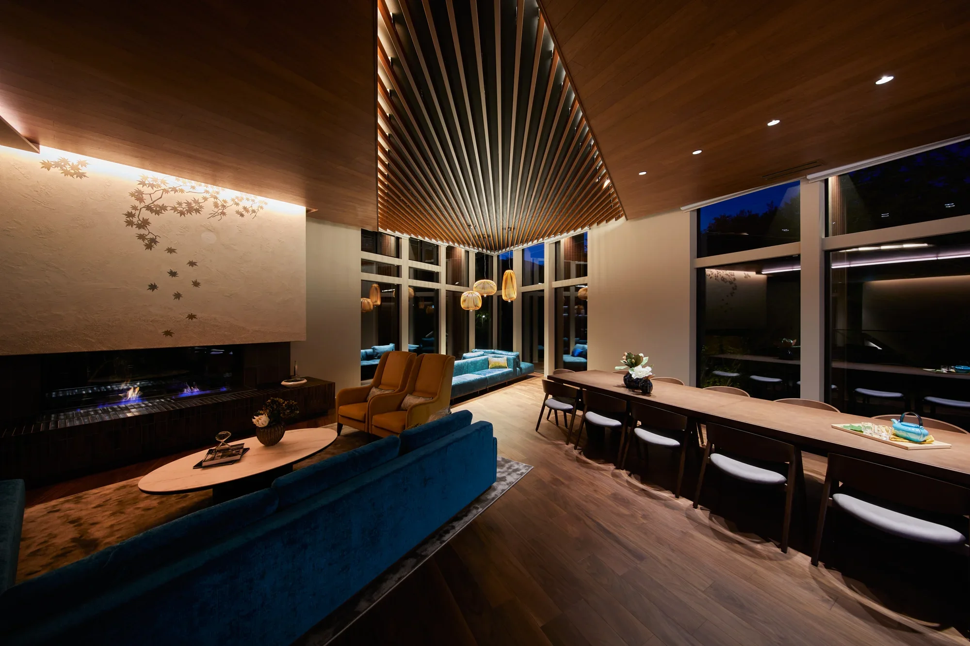 A lit living room with a fireplace and long table at night