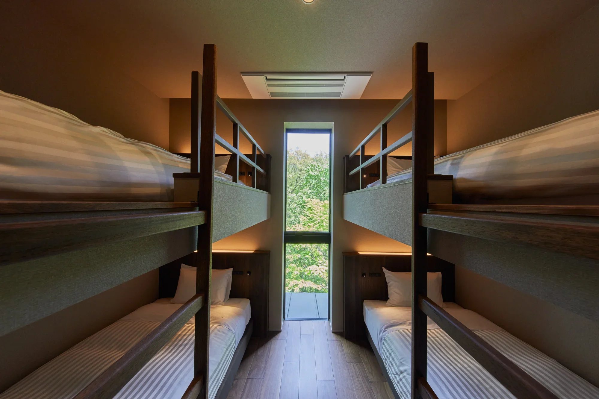 Two pairs of bunk beds beside a tall window