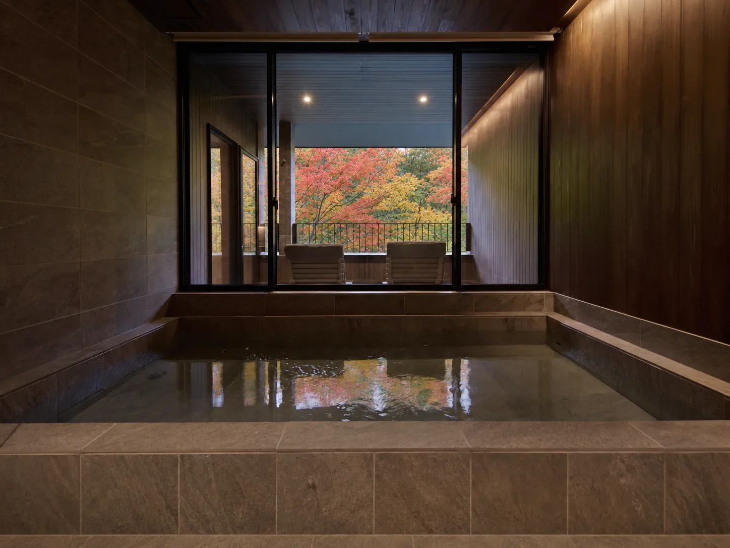 A stone bath facing a balcony and autumn trees